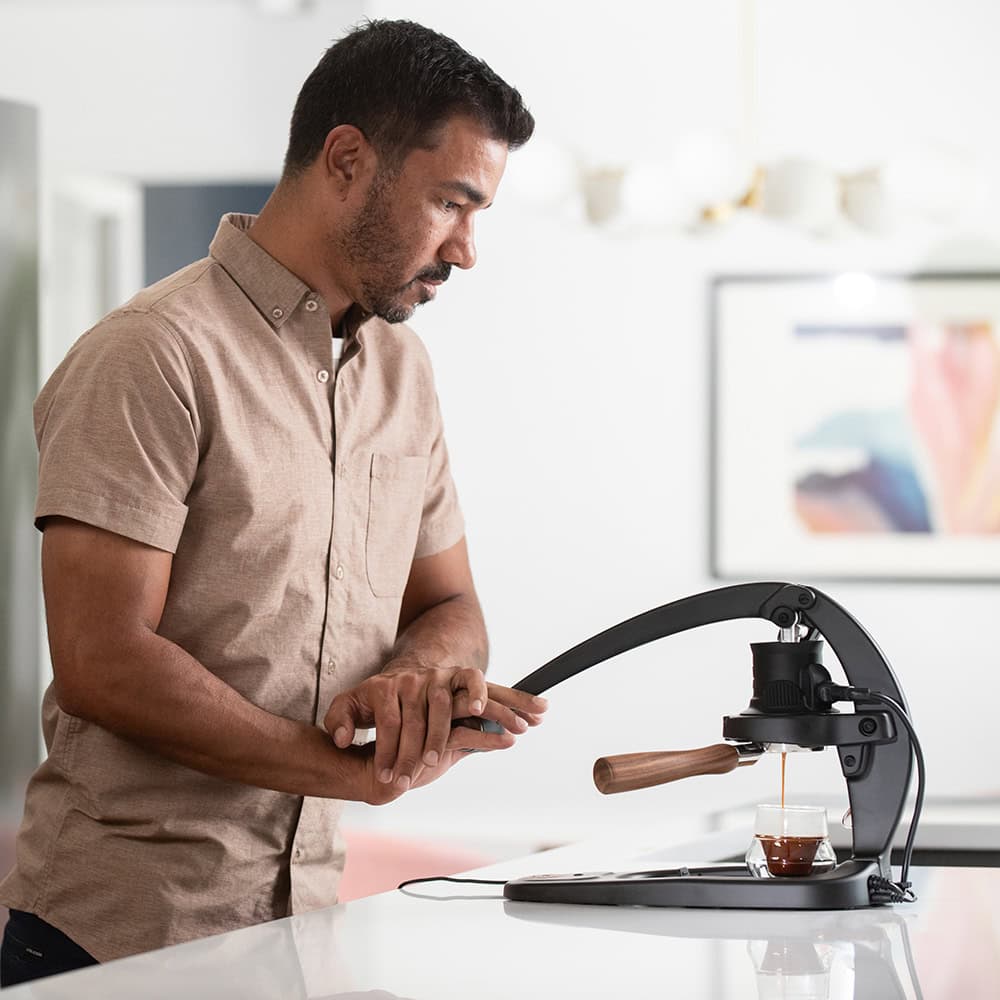 Man using a manual coffee press in a kitchen setting