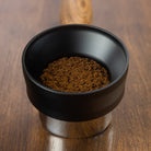 The Flair 49 PRO Magnetic Funnel seated on a portafilter with coffee grounds.