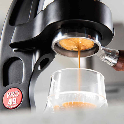Espresso being brewed into a glass from a coffee machine with 'PRO 49' branding.