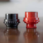 Black and red cylindrical objects on a reflective surface with a neutral background