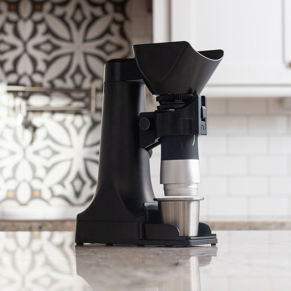 Black and silver kitchen appliance on a countertop with a decorative wall in the background